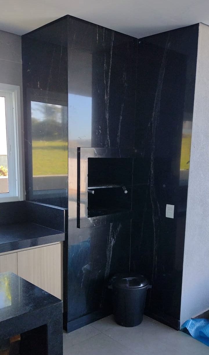 Parede da churrasqueira revestida em granito preto com veios brancos