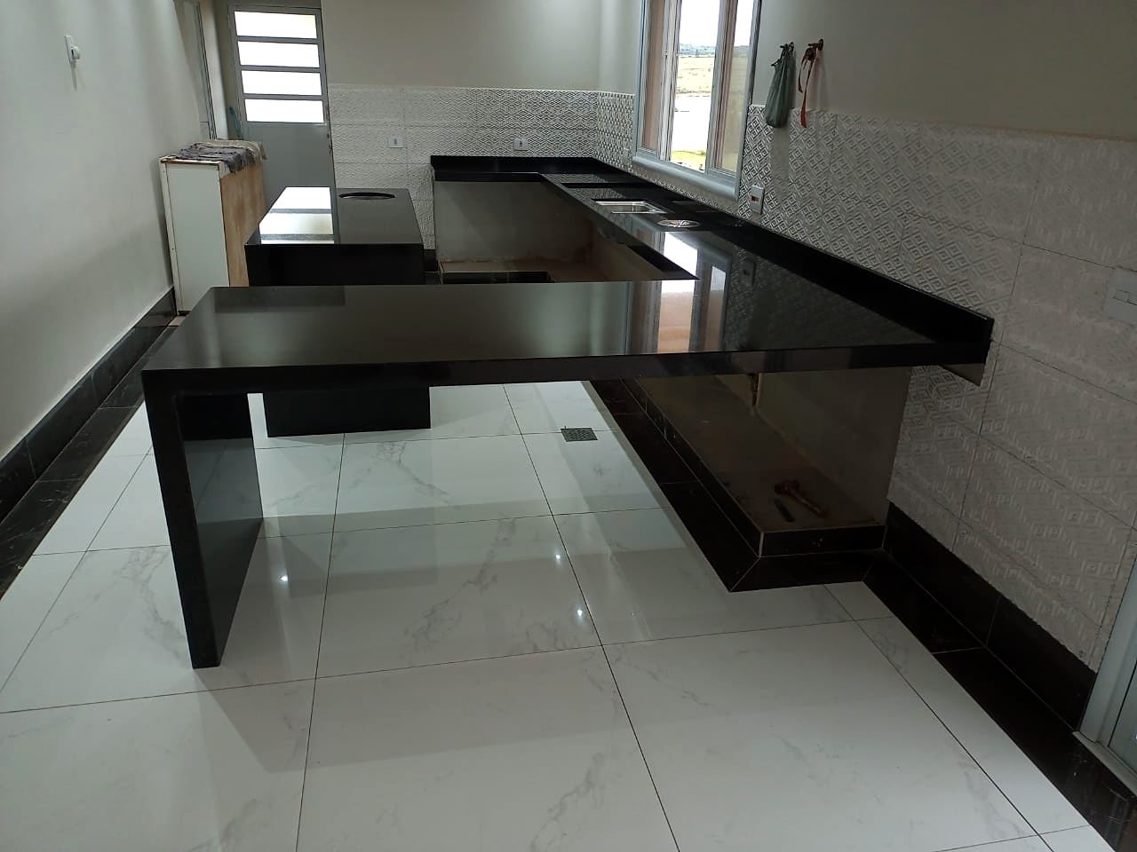 Cozinha com bancada em granito preto, ilha central e pernas em cascata