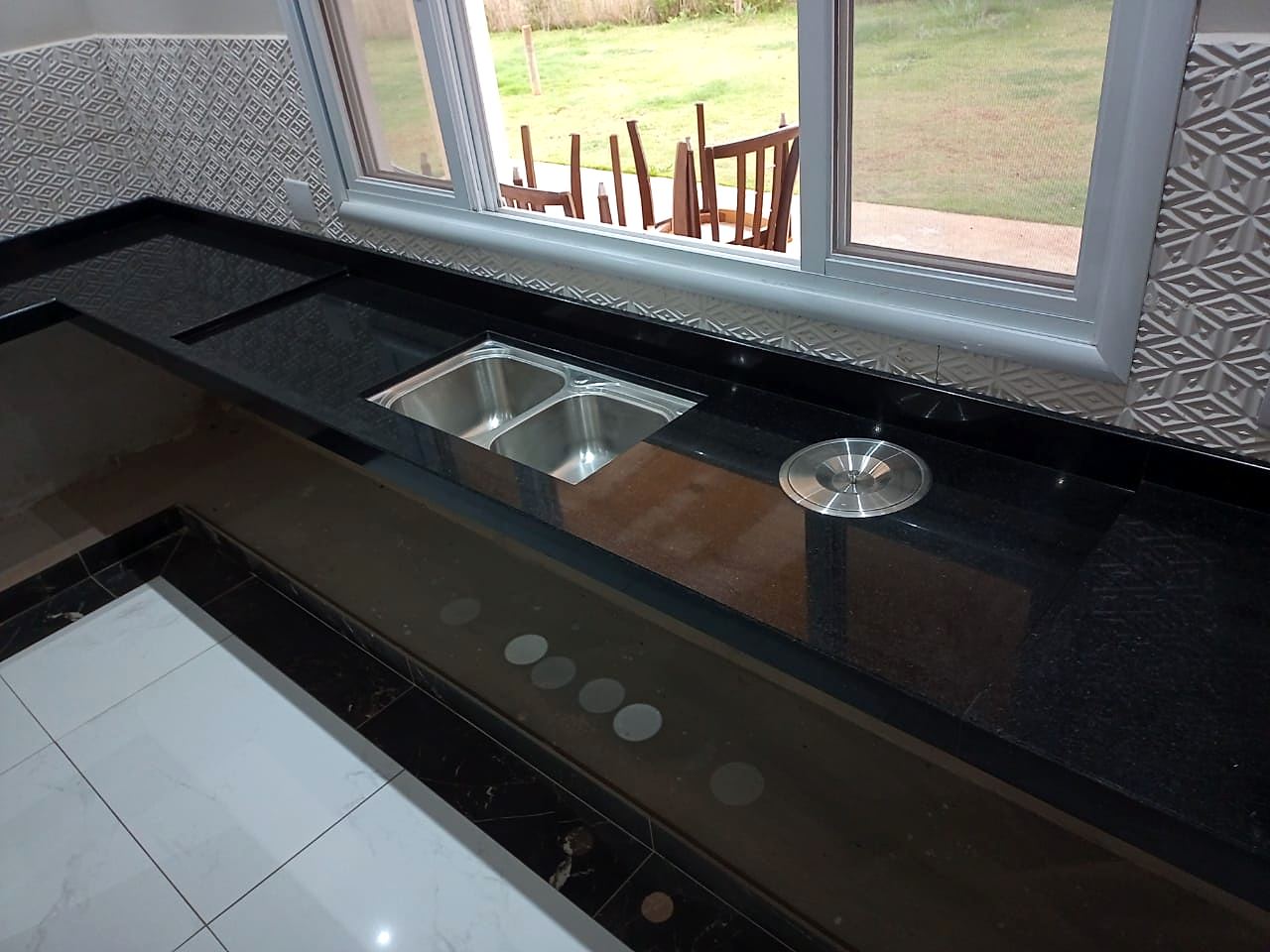 Bancada de granito preto com cuba dupla de inox sob a janela