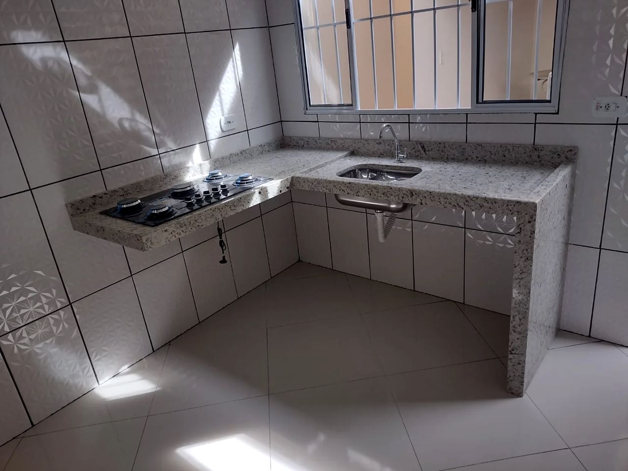 Cozinha em L com bancada de granito Branco Dallas, cooktop e cuba