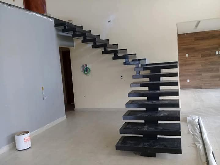 Escada em balanço com degraus de granito preto saindo da parede