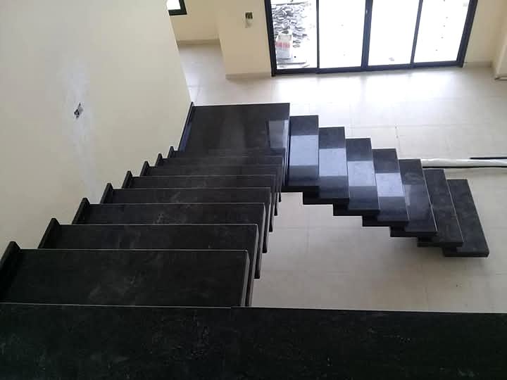 Escada de granito preto vista do alto, com degraus em balanço